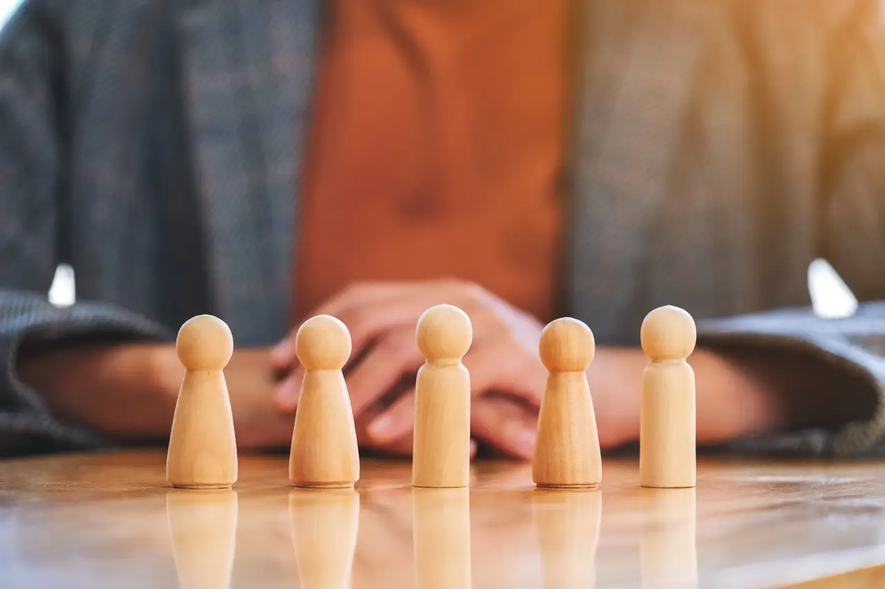 Figurines en bois disposées sur une table dans un bureau, symbolisant la répartition d'un patrimoine entre plusieurs personnes